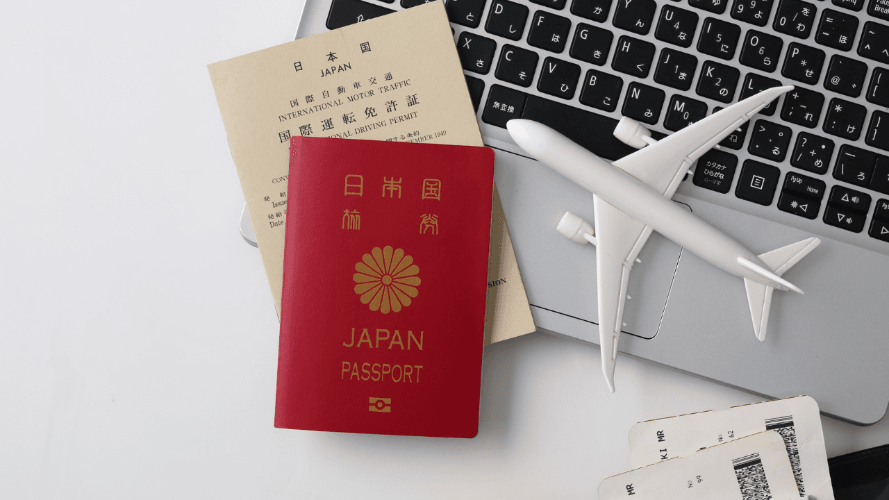 日本のパスポートと飛行機模型・ノートPC(旅行)