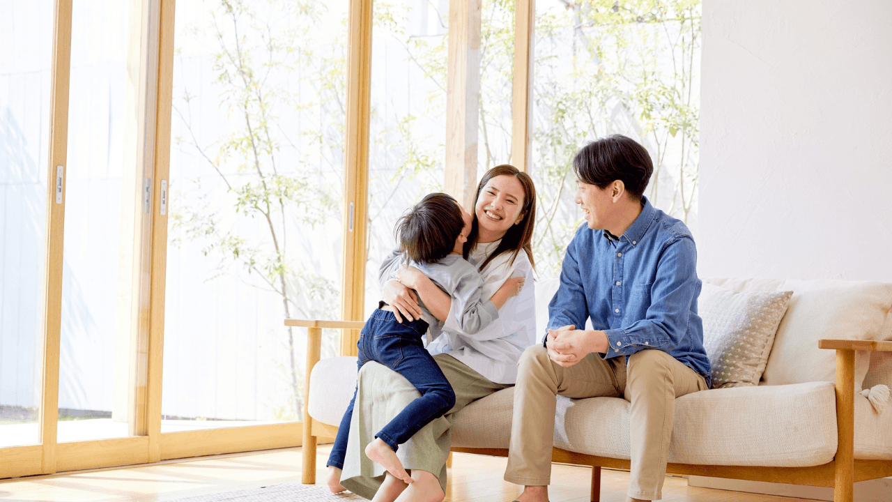 明るいリビングでくつろぐ家族3人