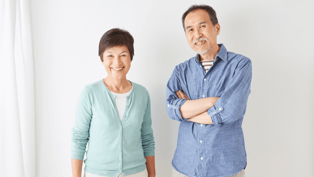 室内で並ぶ笑顔のシニア夫婦