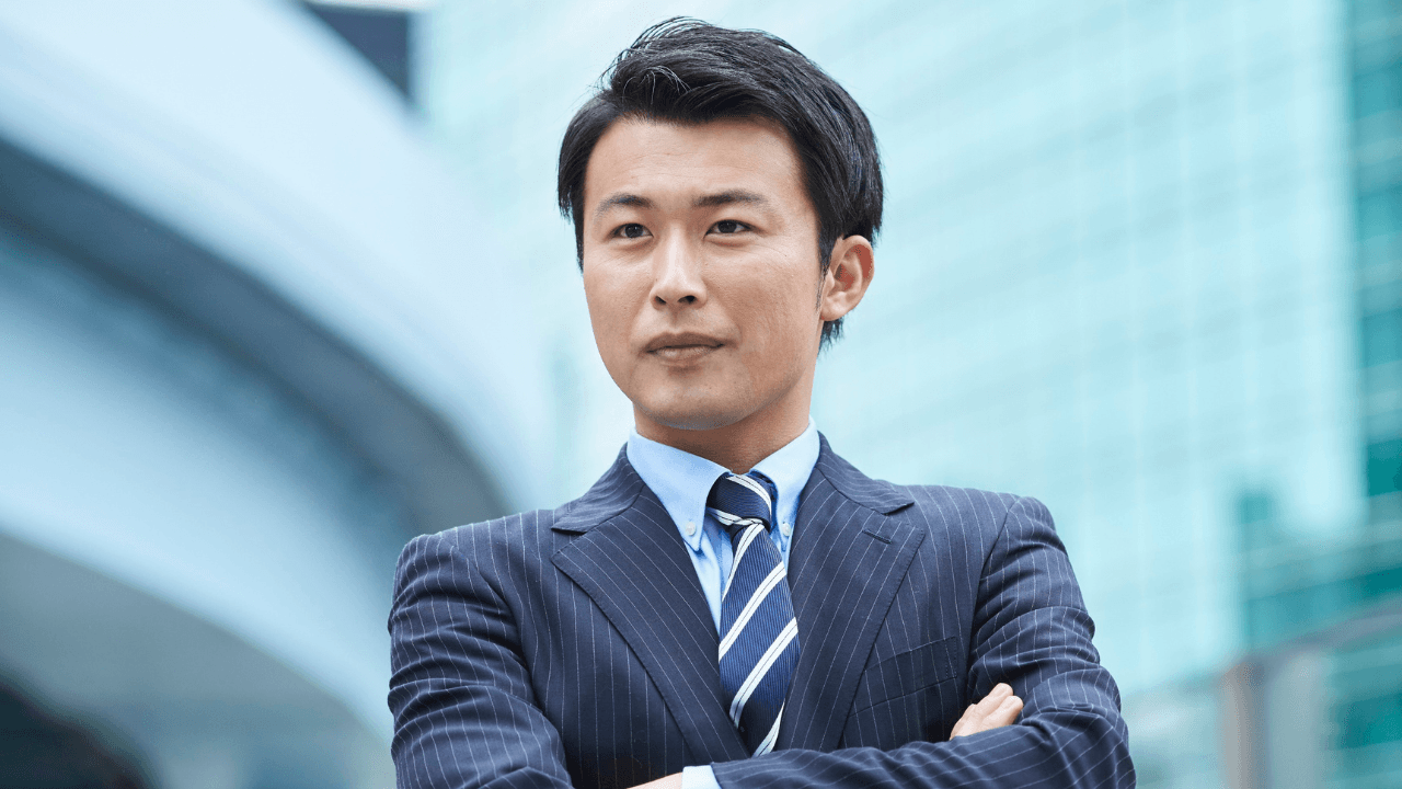 腕を組む自信ありげなスーツ姿の男性