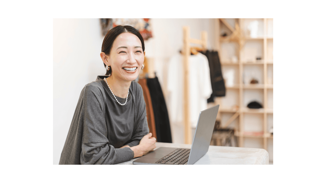 アトリエでノートPCに向かう笑顔の女性